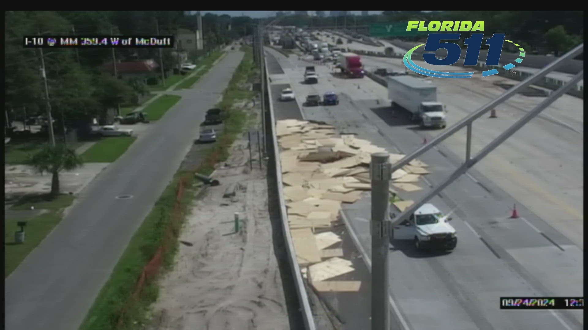 A live highway camera feed shows plywood spilled out from a tractor-trailer onto Interstate 10 in Jacksonville.